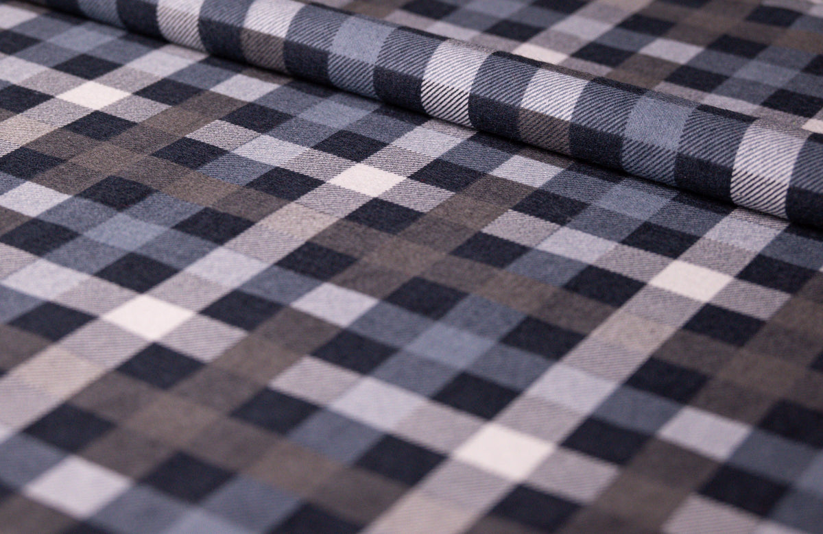 Therapiedecke mit Flanellbezug in Grau Kariert: Aufgerollter Flanellstoff im kleinen Karomuster aus Grau, Blaugrau, Taupe, Weiß und Dunkelblau, schräg fotografiert als Stoffdetail